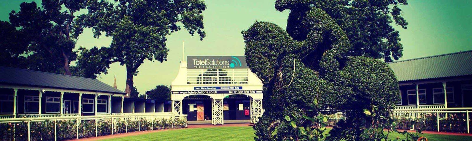 Parade ring at Uttoxeter Racecourse, with a hedge sculpture of a jockey on a horse in the middle.