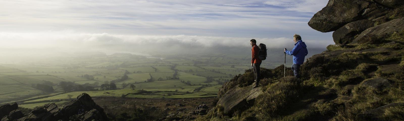 Two men standing on top of a rock, overlooking the Staffordshire county.