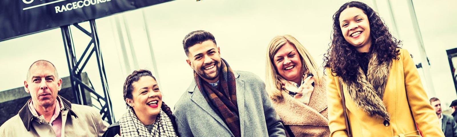 Group of smiling racegoers arriving at Uttoxeter Racecourse.