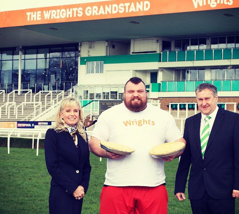A strongman competitor posing for a photo with member of the Uttoxeter team.