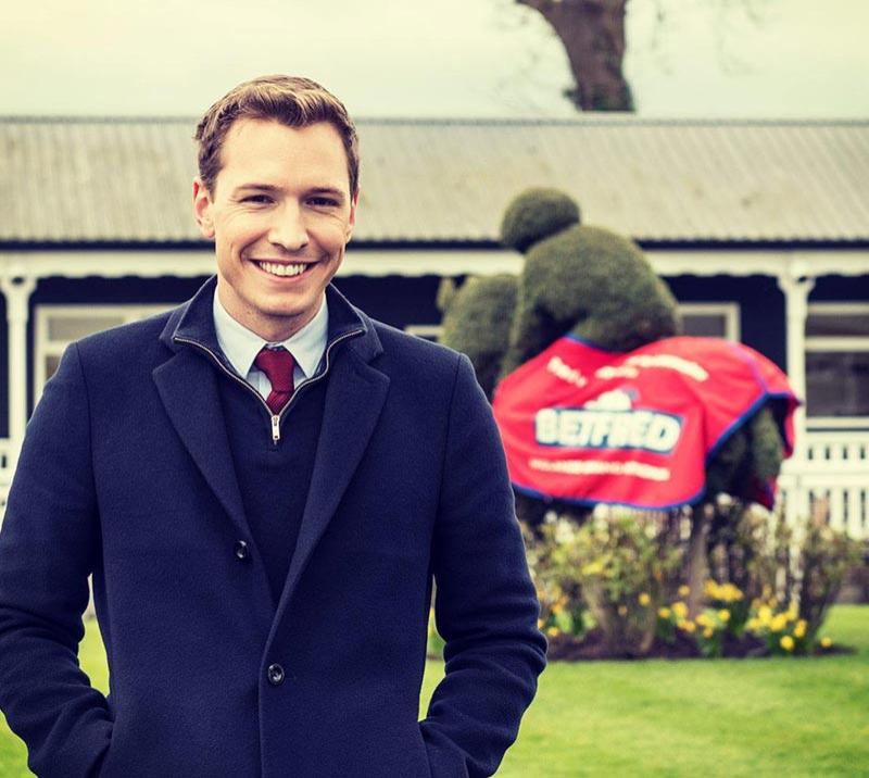 Gentleman posing for a photo with the parade ring behind him.